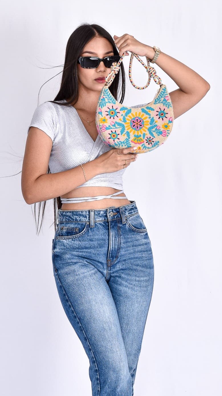 Natalie Crescent Wayuu Bag, a handmade Colombian shoulder bag with beige, pink, and blue tones, handwoven by Wayuu artisans