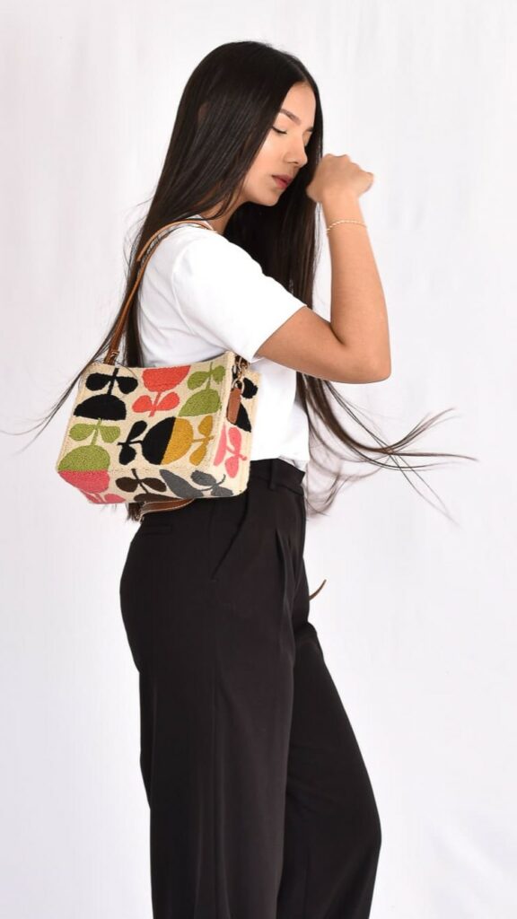 Ruby Wayuu Bag, handcrafted Colombian mochila with beige base and vibrant green, pink, and black woven patterns by Wayuu artisans.
