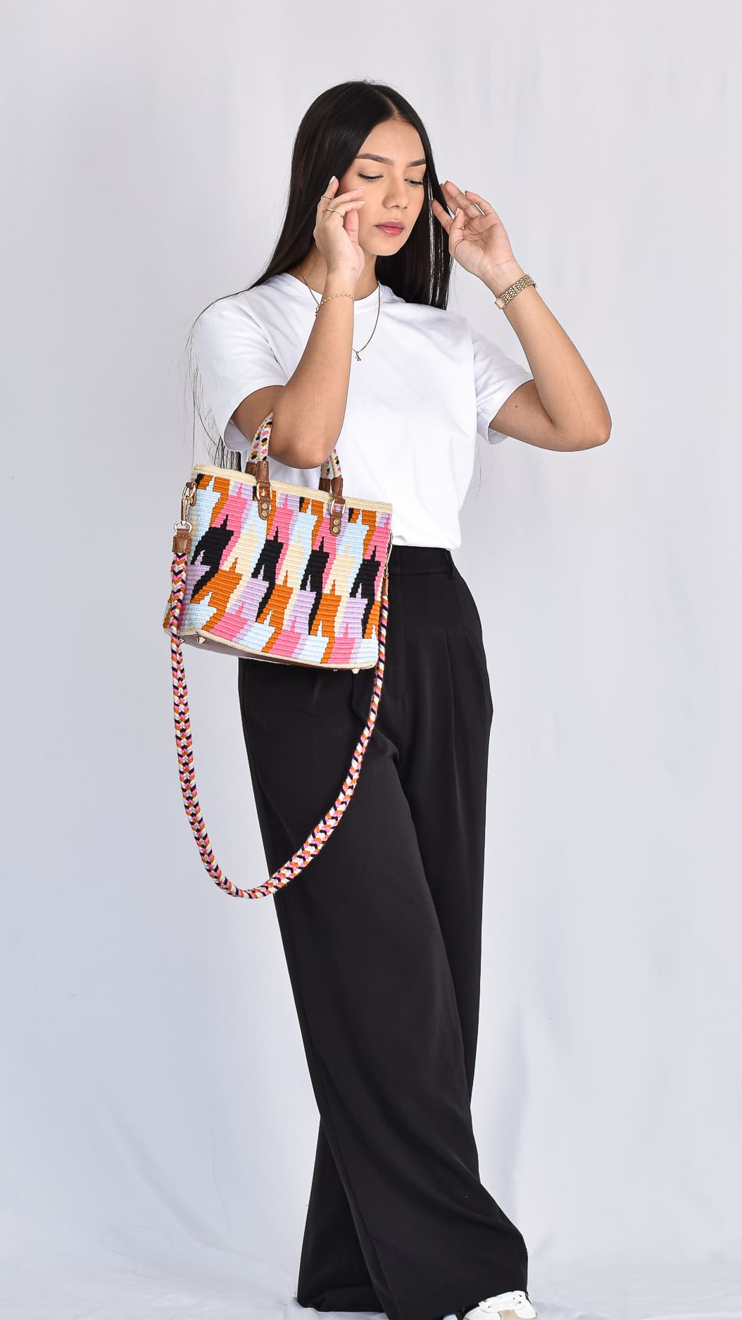 The Anaís Wayuu Handbag, a handmade Colombian bag with vibrant geometric patterns in pink, blue, and black, featuring two straps for versatile use.
